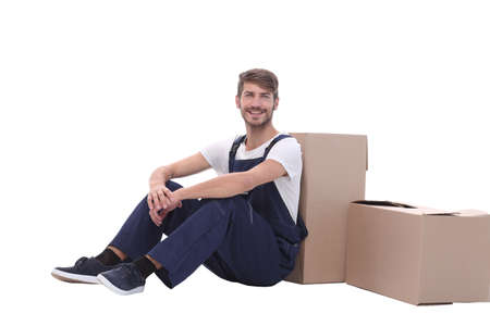in full growth. smiling man sitting near cardboard boxesの写真素材