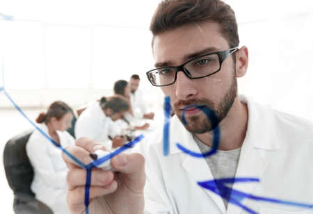 from behind the glass.scientist writes a marker on a glass Board.の写真素材