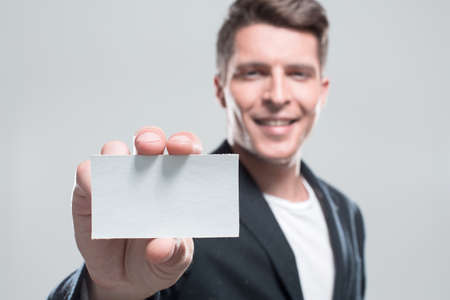 Businessman with arm out in a welcoming gesture over gray backgrの写真素材