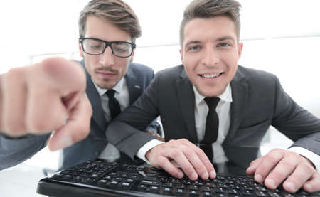 two businessman look at the camera and show with a finger