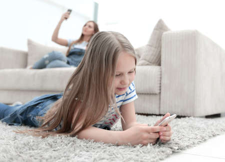 mom and her daughter using their smartphones in the new living room.の写真素材