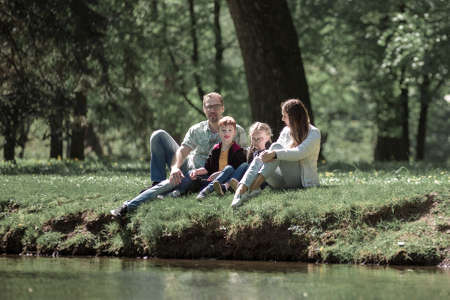 parents with children sitting on the grass in the city Parkの写真素材