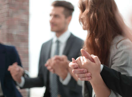 Business group in a circle holding hands indoors