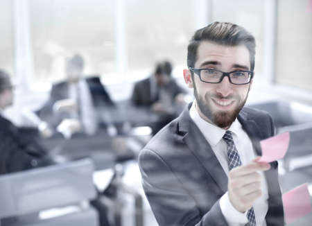 Manager reads a sticky note on a glass Board