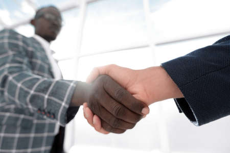 business people shaking hands in a bright office.の写真素材