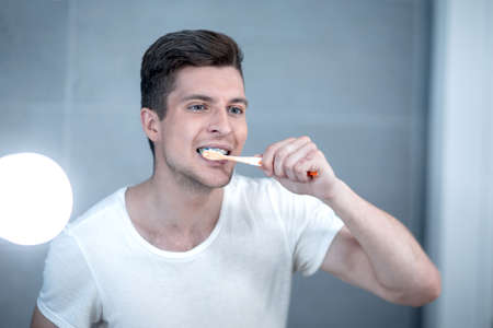 young man brushing his teeth in the bathroomの写真素材