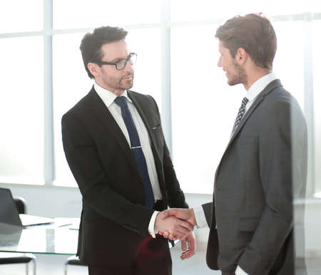 handshake business partners on the background of the workplaceの写真素材