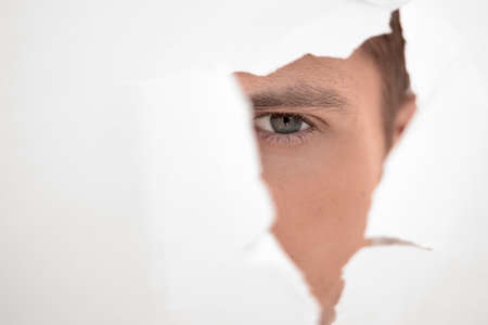 close up. businessman looking through a hole in the paper wallの写真素材