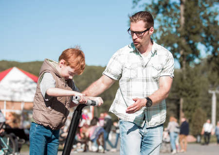 father teaches son to ride a mini-hoverboard in the Park