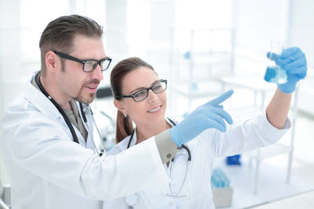 close up.researchers are discussing the liquid in the flask
