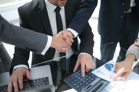 Handshake across the table of financial partners