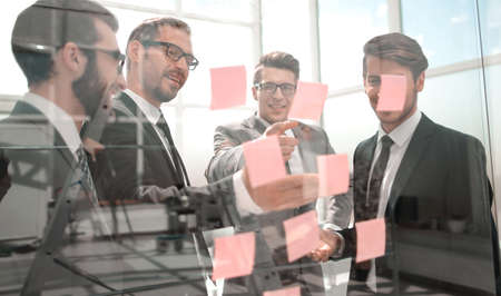 business colleagues reading sticky notes on glass