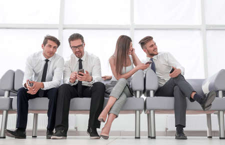 business team with mobile phones sitting in the lobby of the office