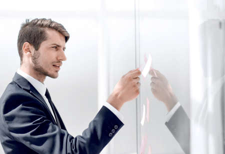 businessman reading sticky notes on glassの写真素材