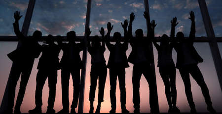 silhouette of a group of business people raising their handの写真素材