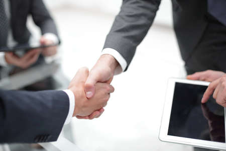 Men shaking hands with smile at office with their coworkers.