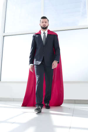 businessman in a Superhero cloak standing in a bright officeの写真素材