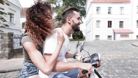 Stylish young couple sits a scooter in the street.の写真素材