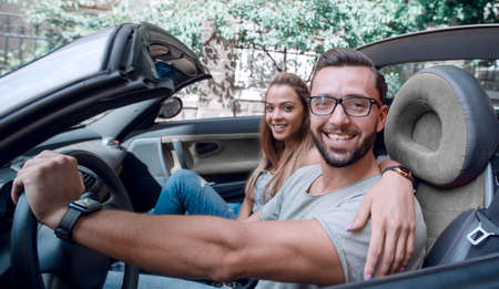 young couple inside a convertible car for a day trip.の写真素材