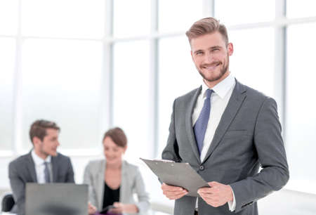 smiling businessman with a clipboard on the background of the office