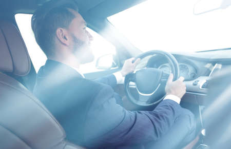 businessman sits at the wheel in his car and looks at the roadの写真素材