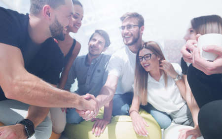 young people shaking hands in a circle of friends