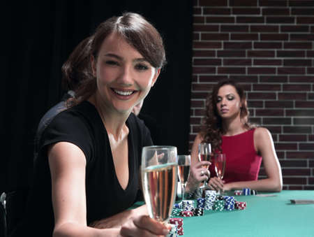 portrait of smiling woman with drink playing pokerの写真素材