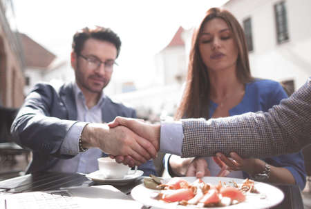 handshake colleagues in a street cafe