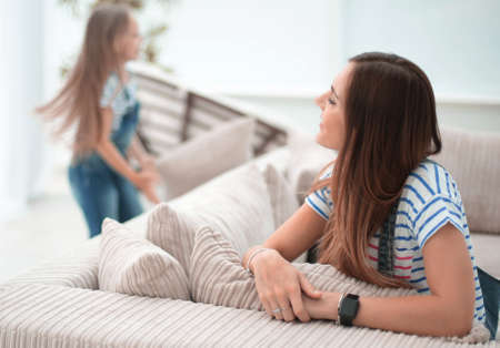 young woman sitting on sofa and looking into spacious living roomの写真素材