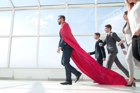 side view.businessman superhero goes ahead of his business team