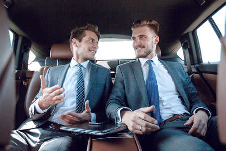 business colleagues talking, sitting in the back seat of a carの写真素材