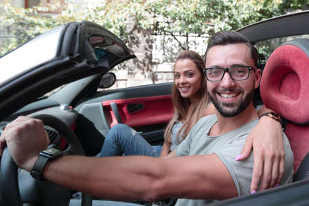 young couple inside a convertible car for a day trip.の写真素材