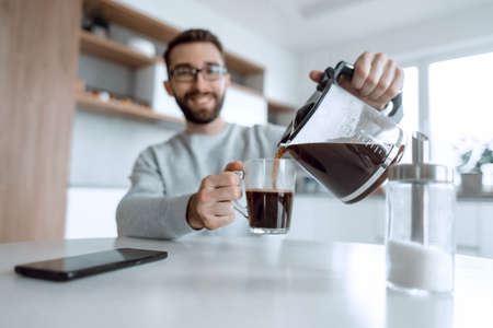attractive man pours himself a cup of delicious coffeeの写真素材