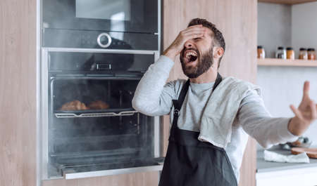 surprised man standing near the oven with burnt croissants.の写真素材