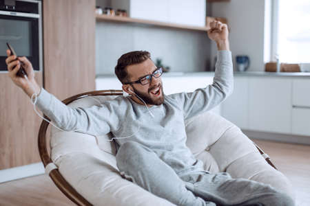 happy man enjoying his favorite music while sitting in a chairの写真素材