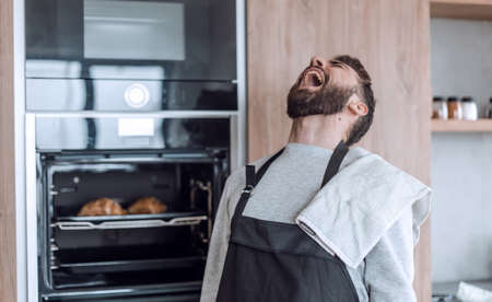 surprised man standing near the oven with burnt croissants.の写真素材