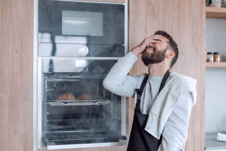 surprised man standing near the oven with burnt croissants.の写真素材