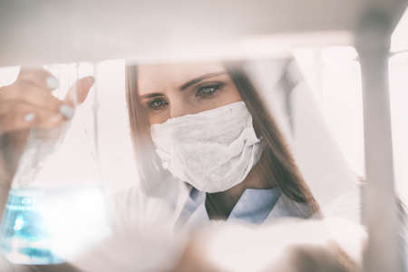 close up. woman doctor in protective mask with flaskの写真素材