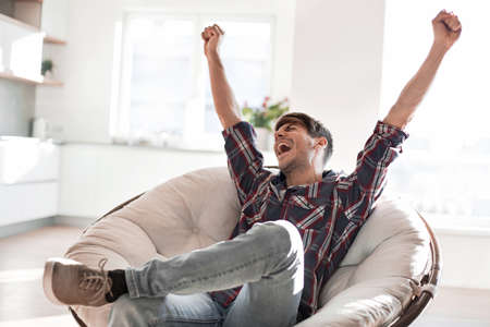 happy young man sitting in a chairの写真素材