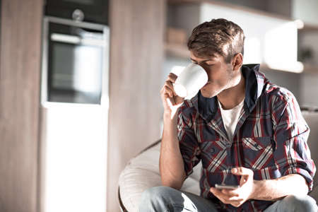 attractive young man drinking coffee and reading SMS.の写真素材