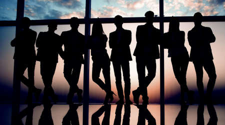group of happy young business people standing near a large office windowの写真素材