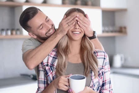 happy man joking with his girlfriend in the kitchen in the morningの写真素材
