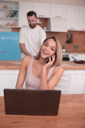 modern young woman talking on mobile in the kitchenの写真素材