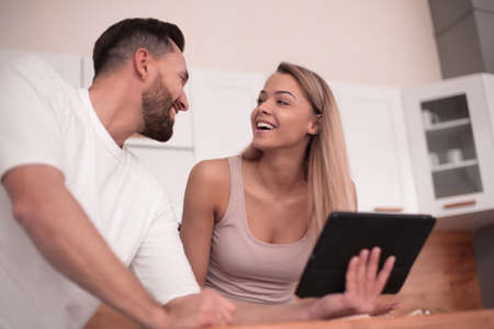 Young couple with digital tablet sitting in kitchen