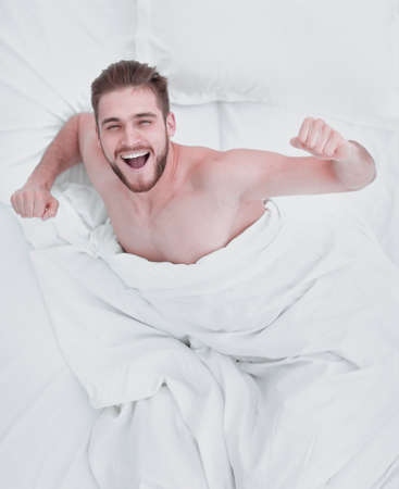 top view. happy man waking up in a comfortable bedの写真素材