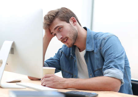 sad businessman with a coffee Cup looking at his computer monitorの写真素材