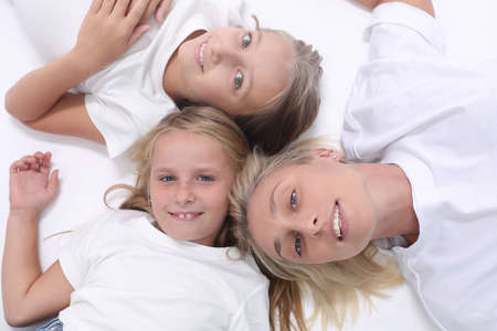 happy mother and daughters lying down togetherの写真素材