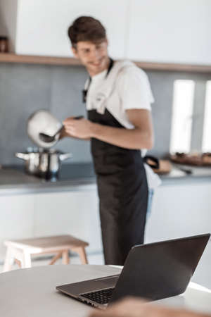 young man reading a recipe for soup in a laptopの写真素材