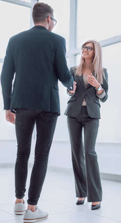smiling employees discuss something standing in the office corridor