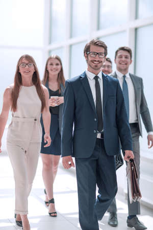 confident businessman and his business team passing through the office corridorの写真素材